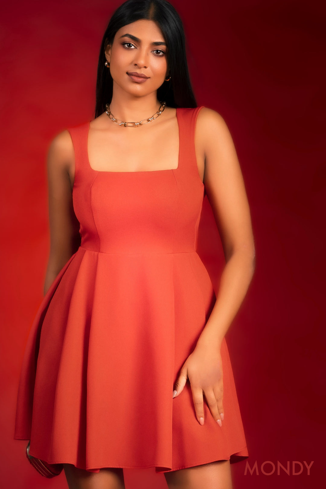 Woman wearing a red dress against a red background with 'MONDY' branding.